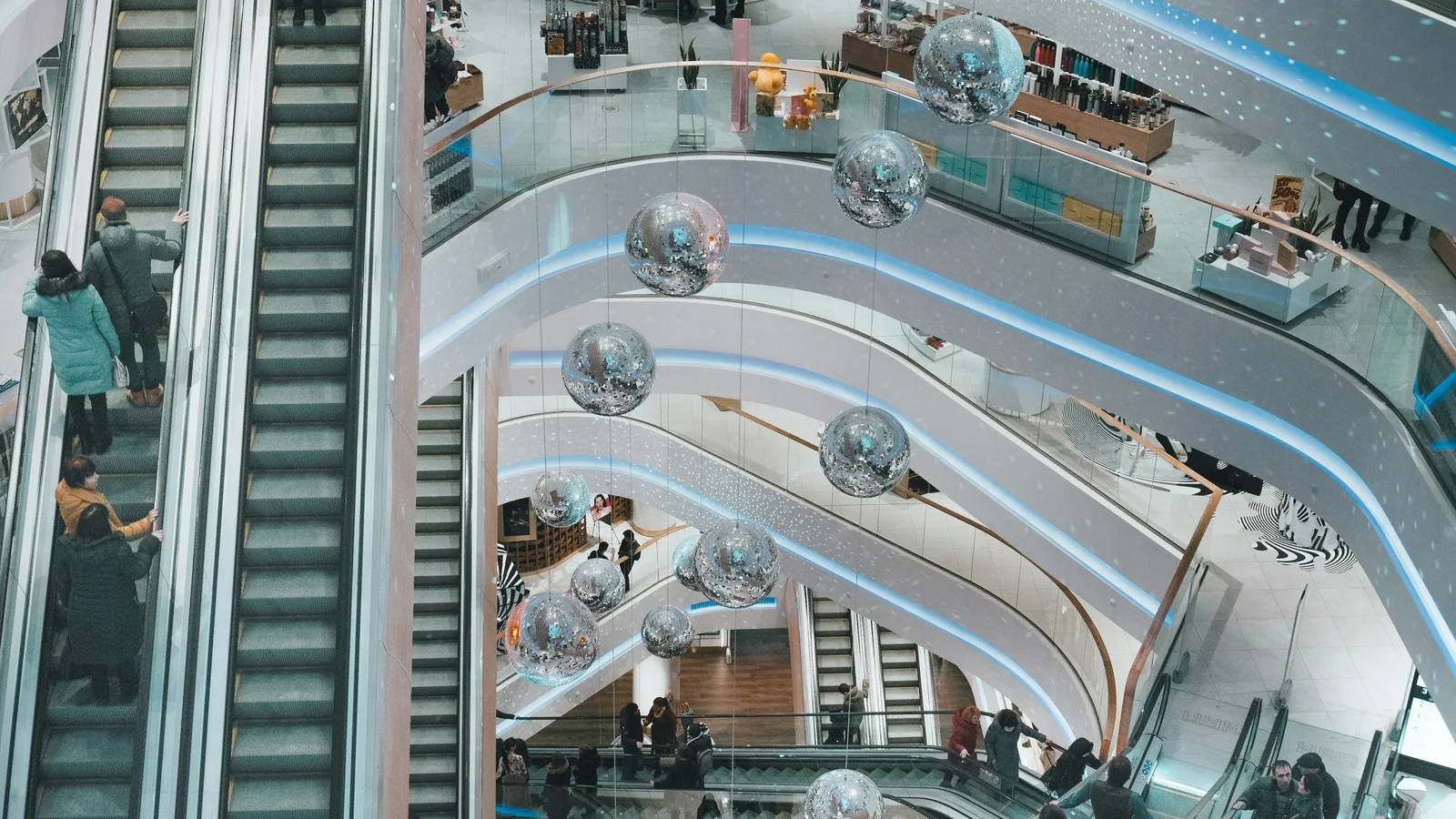 Shoppers on escalators in a multi-level mall atrium, the kind of space used for a launch pop-up