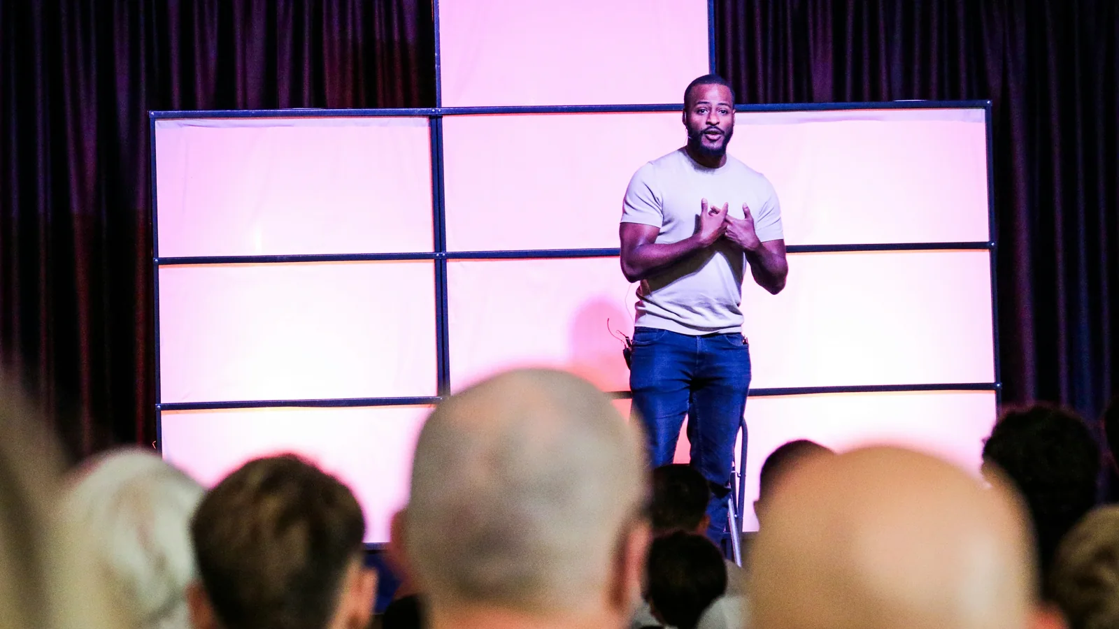 Speaker telling a founder story on a pink-lit stage at an evening product launch